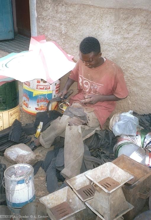 Башмачник на рынке вырезает обувь из старых автопокрышек. Эфиопия.